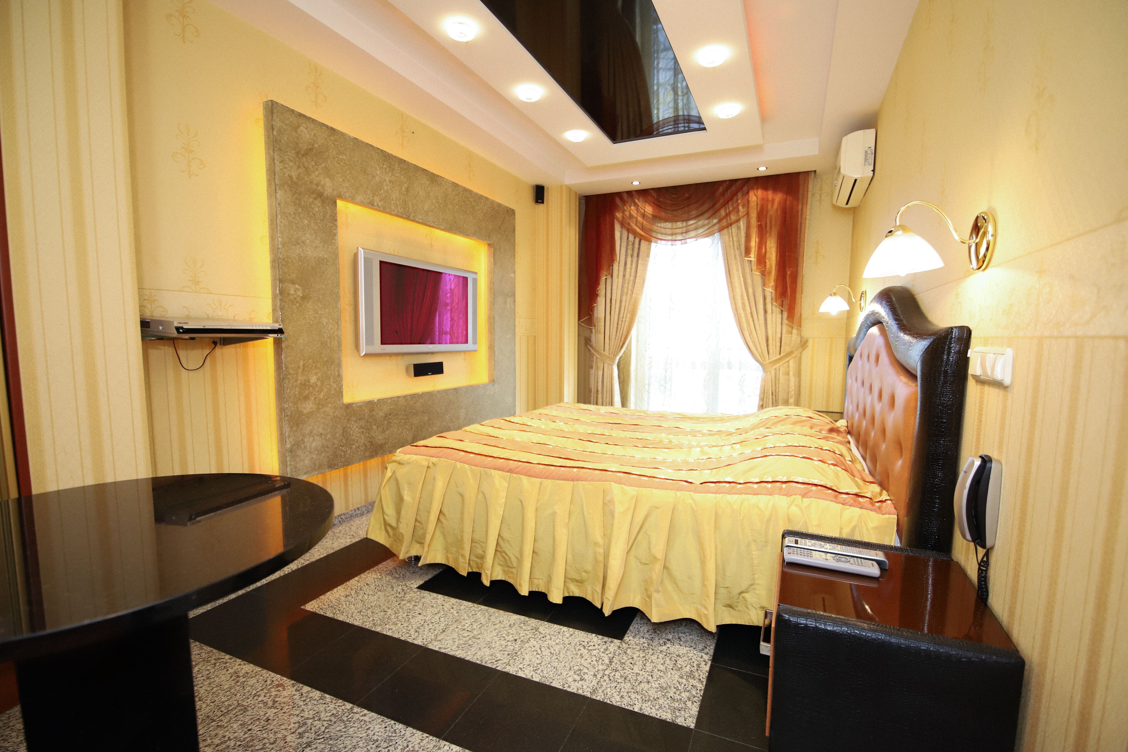A hotel room with a bed, a TV mounted on the wall, a desk, and a chair.