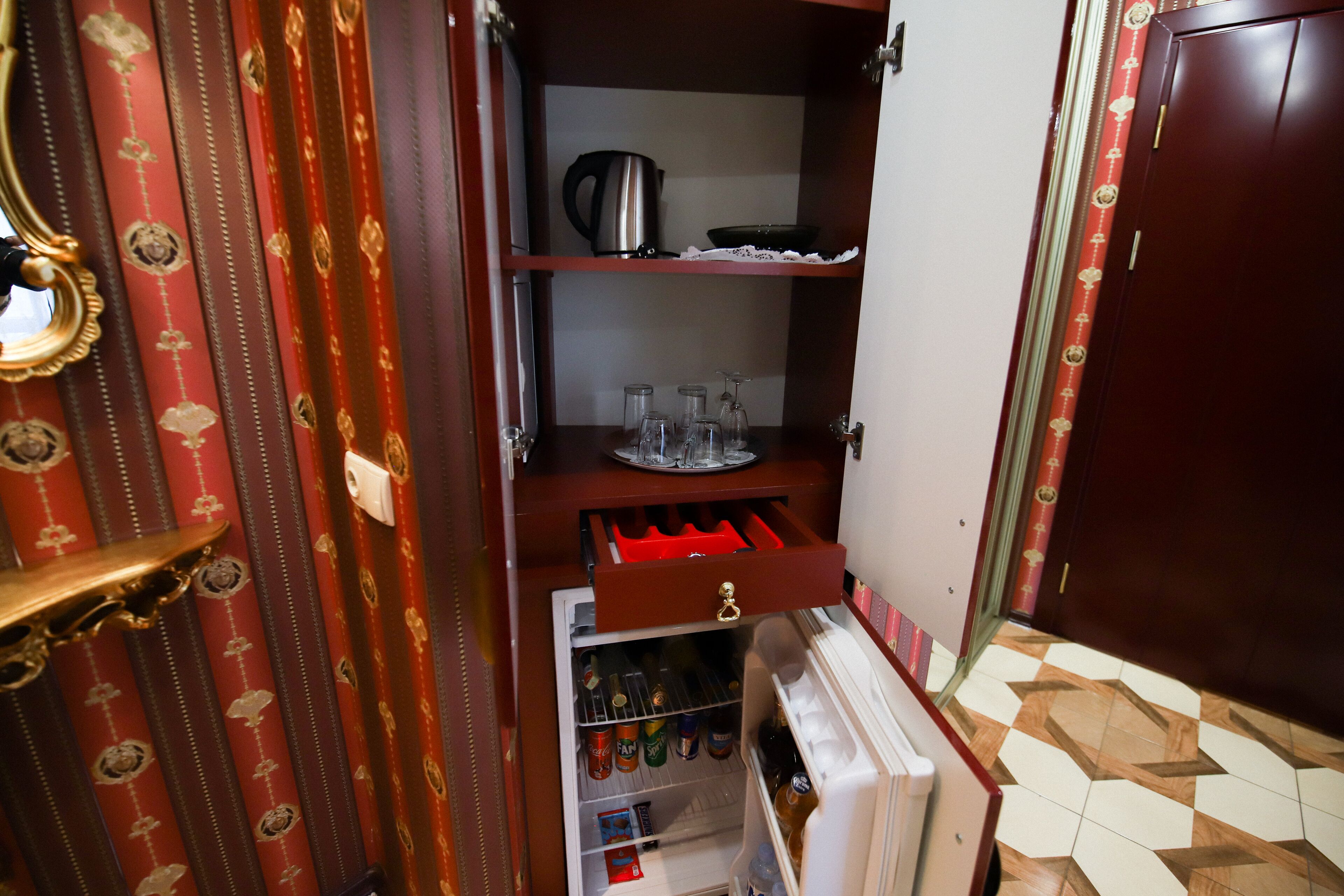 A compact kitchen with a refrigerator, a coffee maker, and a wine glass holder.