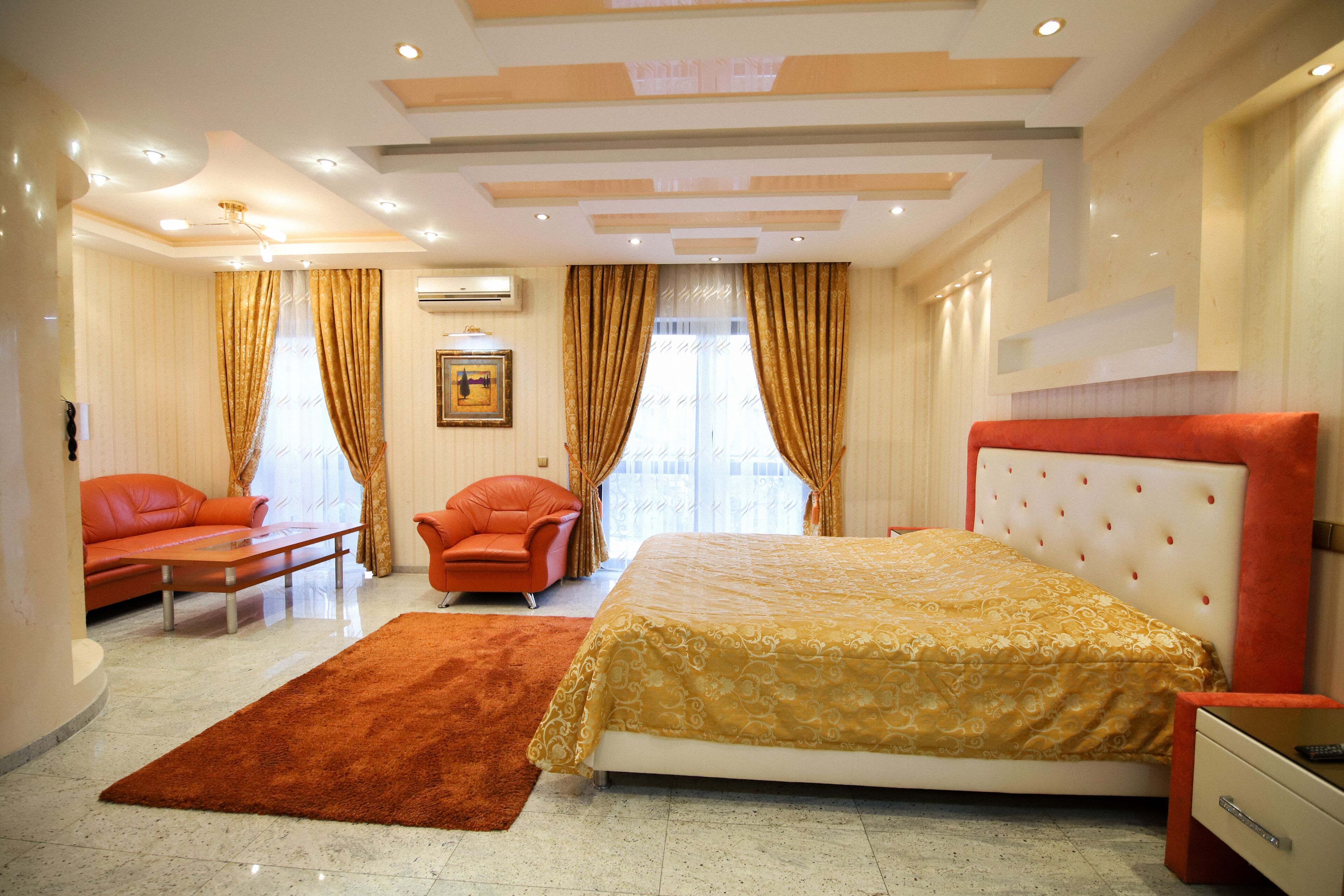 A bedroom with a bed, a sofa, a chair, and a carpet.