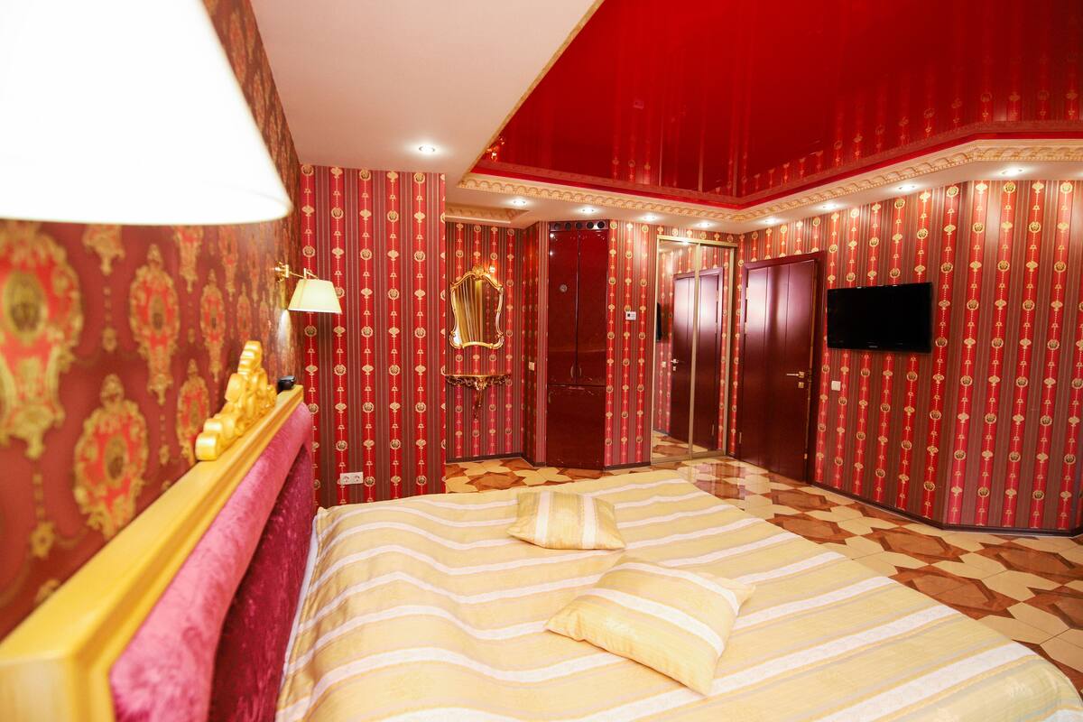 A hotel room with a bed, a television, a mirror, and a wardrobe.