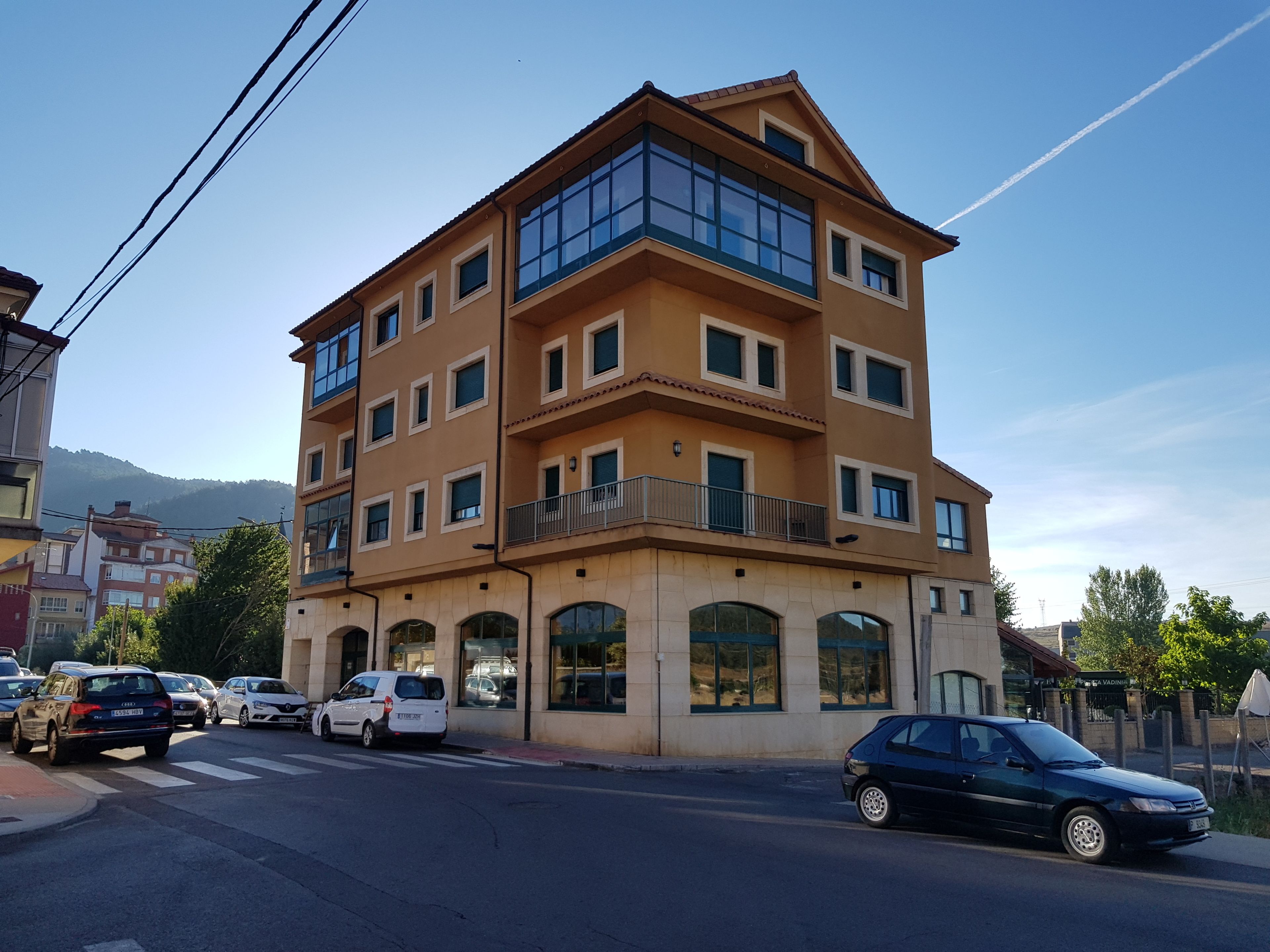 A multi-story building with a flat roof, large windows, and a balcony on the second floor.