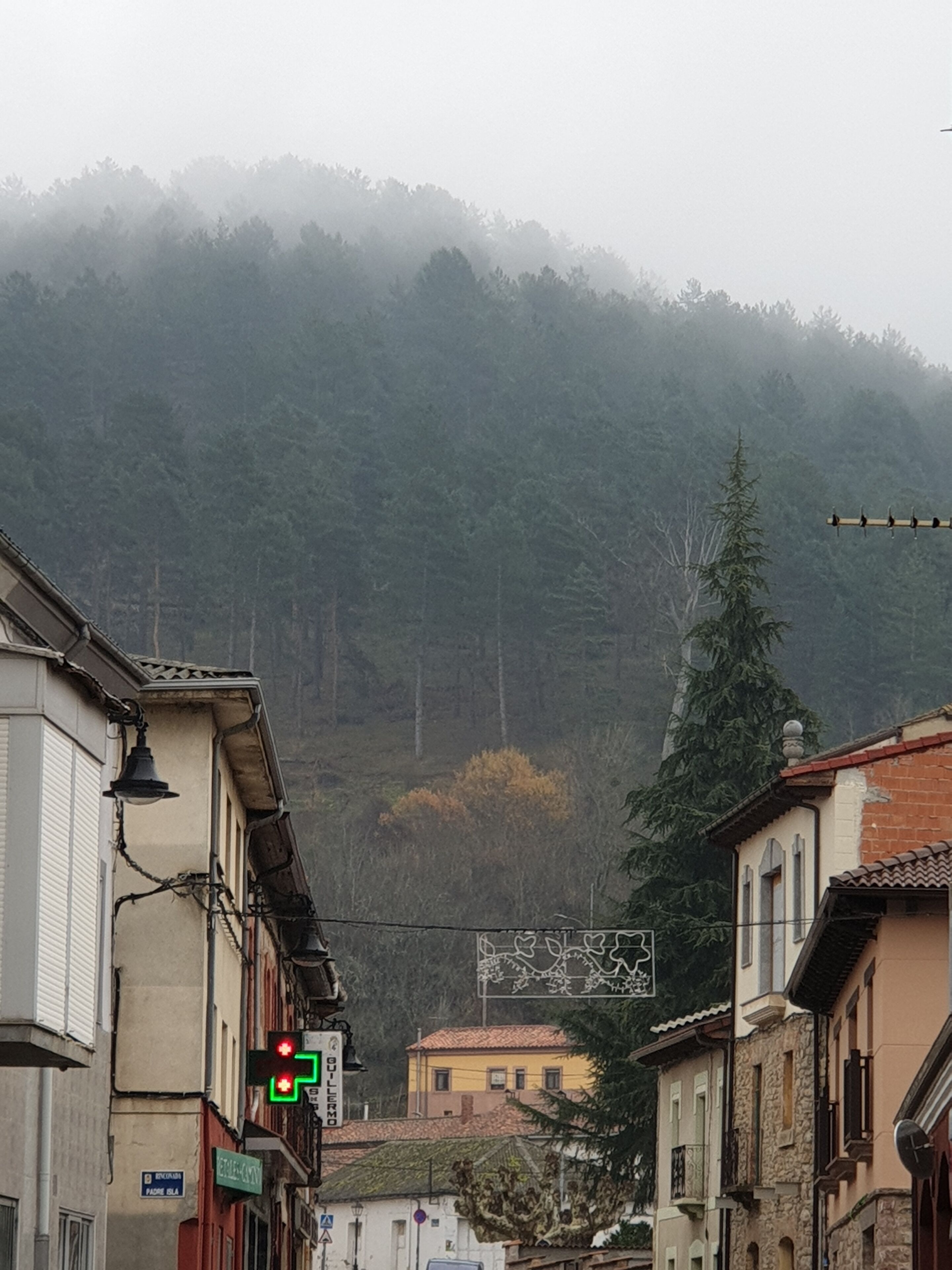 Una calle con edificios y una montaña al fondo.