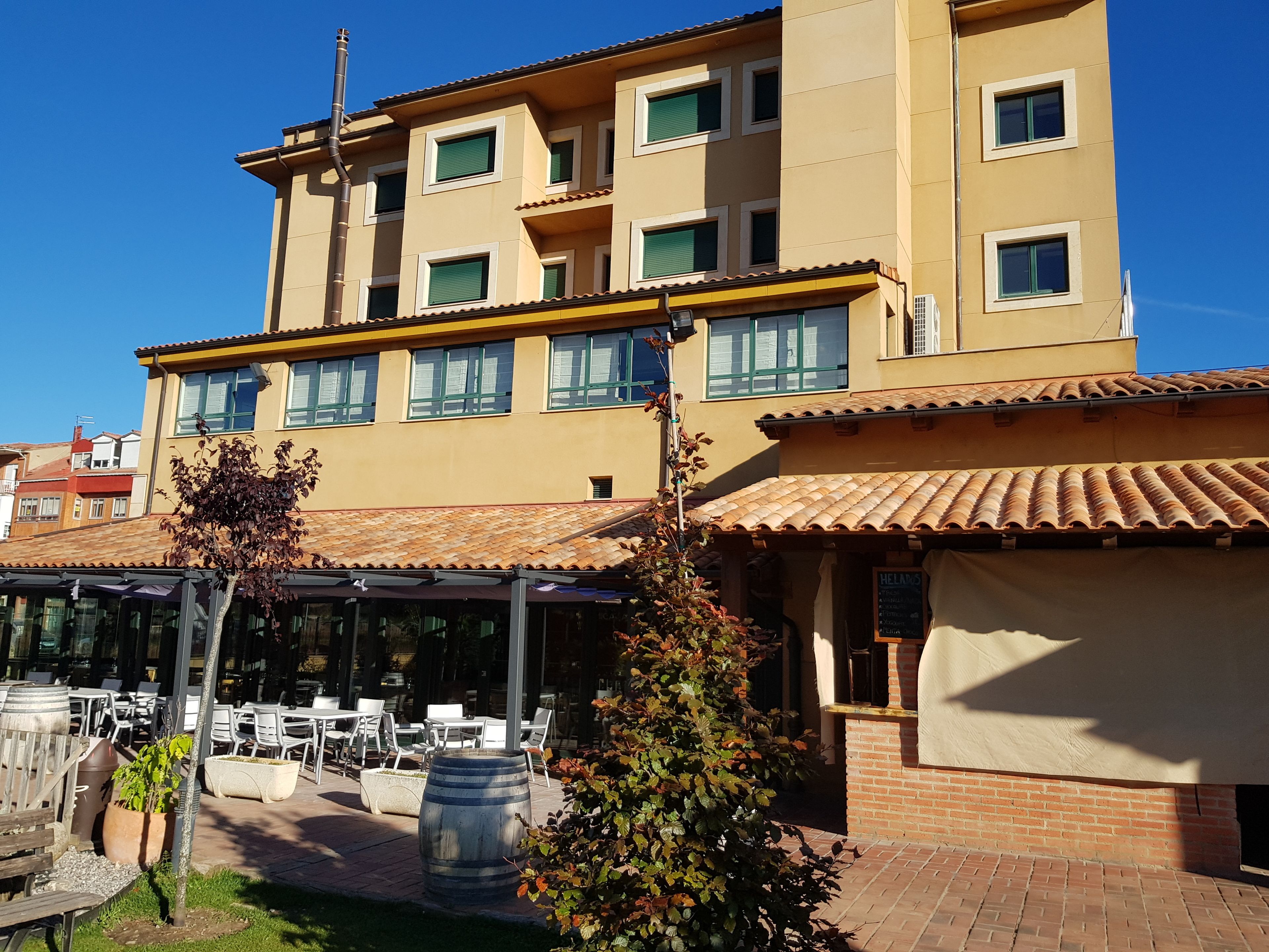 Un edificio de varios pisos con una terraza que ofrece asientos exteriores y un bar.