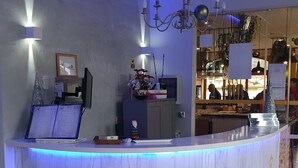 Un comptoir d’accueil avec une pancarte indiquant « RÉCEPTION » et « Entrée de l’hôtel et du spa Vadinia ».