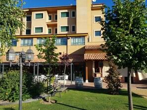 Un immeuble à plusieurs étages doté d’une cour intérieure aménagée avec des sièges, un petit arbre et un banc.