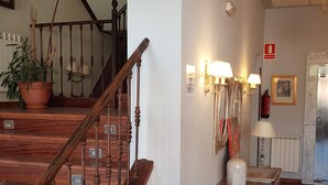 Un escalier en bois, agrémenté d’un pot de fleurs, un luminaire fixé au mur et un extincteur.