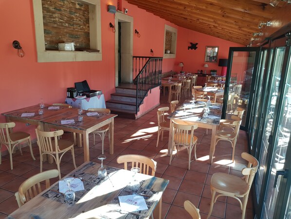 A restaurant with wooden tables and chairs, a staircase, and a pink wall. - Hotel Spa Puerta Vadinia (Cistierna)