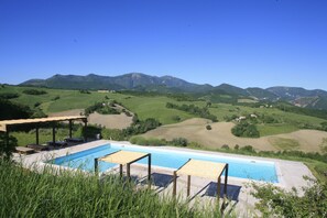 Una piscina al aire libre de temporada, sombrillas