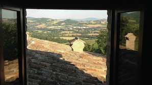 Vista a través de una ventana de una construcción de ladrillo, con un paisaje rural de fondo.