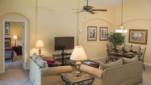 A living room with a sofa, coffee table, TV, and dining area with chairs and a table. - Ip60305 - Highgate at Legacy Park - 4 Bed 3 Baths Villa (Davenport)