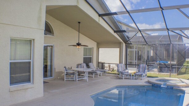 A covered outdoor swimming pool area with lounge chairs and a ceiling fan. - Ip60305 - Highgate at Legacy Park - 4 Bed 3 Baths Villa (Davenport)