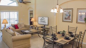 A spacious living room with a beige sofa, a dining table set for four, and a ceiling fan. - Ip60305 - Highgate at Legacy Park - 4 Bed 3 Baths Villa (Davenport)