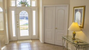 A hallway with a white door, a glass console table with a lamp, and a framed picture on the wall. - Ip60389 - Highlands Reserve - 5 Bed 3 Baths Villa (Davenport)