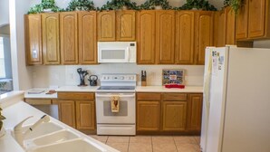 A kitchen with wooden cabinets, a white microwave, a stove, and a refrigerator. - Ip60389 - Highlands Reserve - 5 Bed 3 Baths Villa (Davenport)