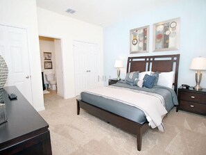 A bedroom with a large bed, two bedside tables with lamps, a dresser, and a door leading to another room. - Fv62387 - The Dales at West Haven - 7 Bed 6 Baths Villa (Davenport)