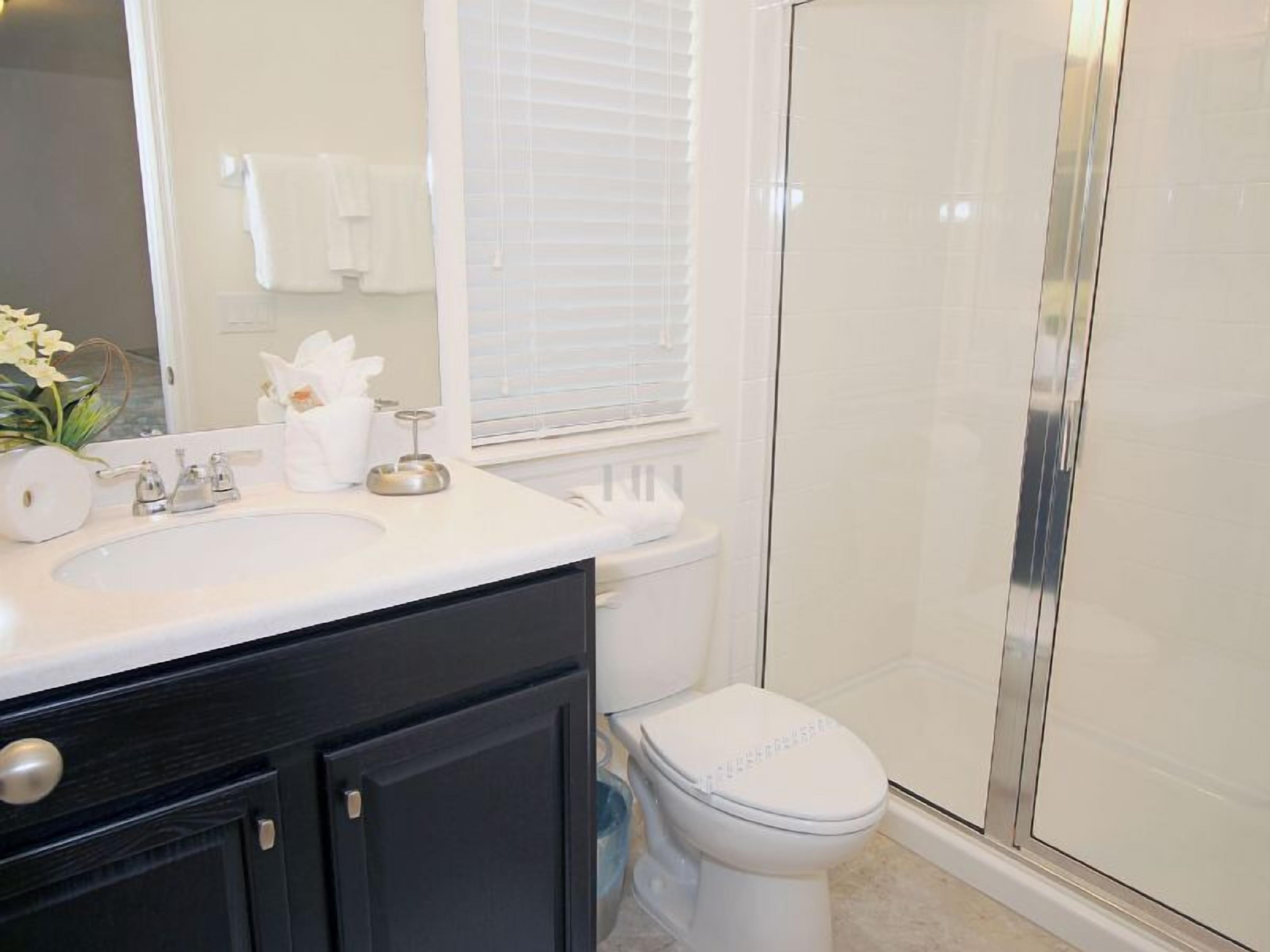 A bathroom with a white sink, a toilet, and a glass shower enclosure.