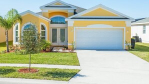 A two-story house with a garage, a small front yard with a tree, and a clear blue sky. - Fv51890 - Crystal Cove - 4 Bed 3 Baths Villa (Kissimmee)