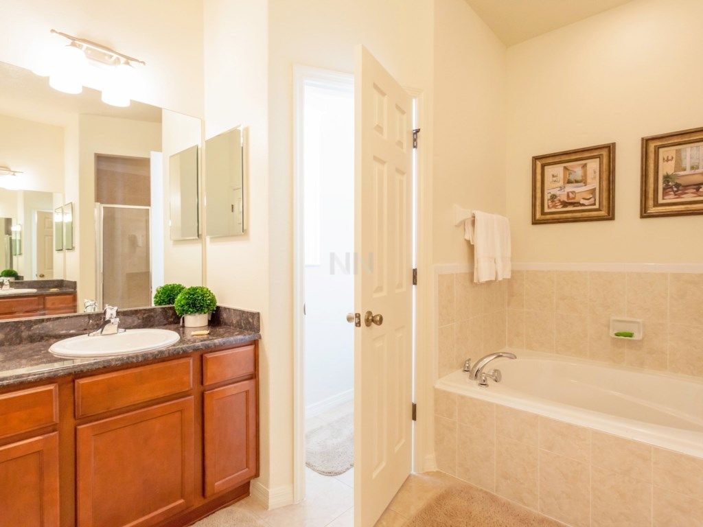A bathroom with a sink, vanity, and bathtub.