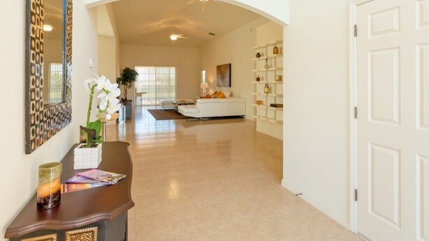A spacious hallway with a white door on the right, a white sofa in the background, and a decorative mirror on the left. - Fv51890 - Crystal Cove - 4 Bed 3 Baths Villa (Kissimmee)