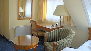 Une chambre d’hôtel équipée d’un bureau, d’une chaise, d’une lampe et d’un lit.