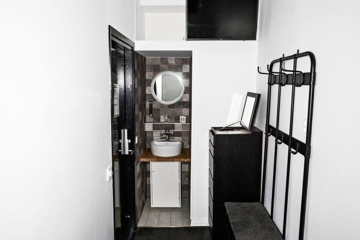 Un baño moderno y estrecho con lavamanos integrado, un espejo y una lámpara colgante.