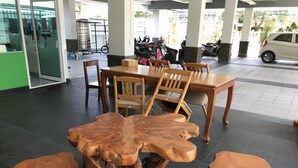 A dining area with a wooden table and chairs, a large wooden centerpiece, and a tiled floor. - Tree House Apartment Songkhla (Songkhla)
