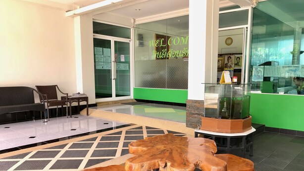 A reception area with a wooden table, chairs, and a glass display case. - Tree House Apartment Songkhla (Songkhla)