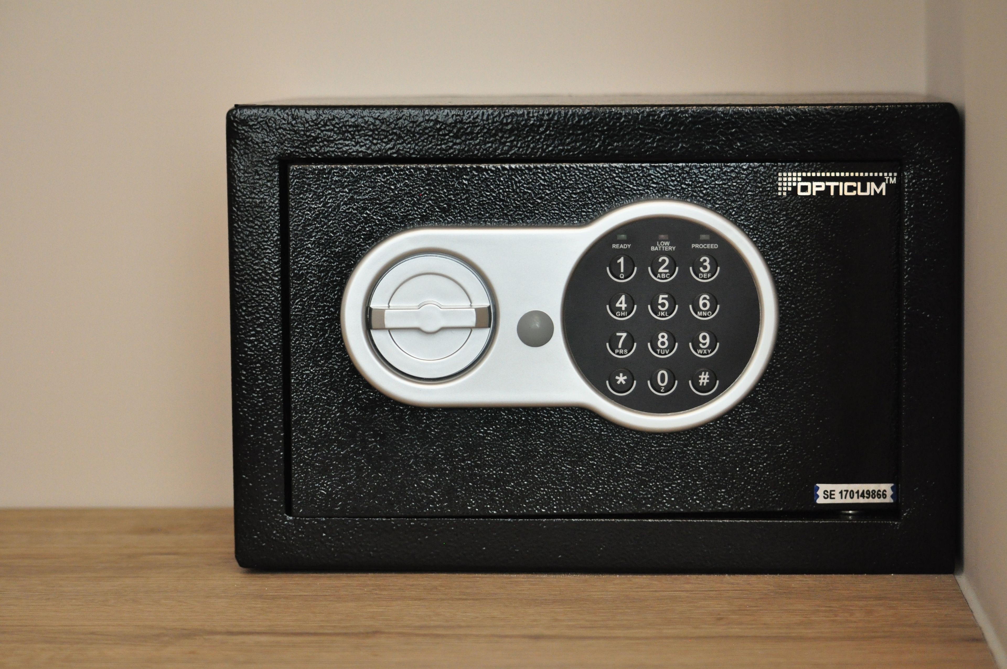 Een zwarte kluis met een keypad en sleutelgat, met het Opticum logo.