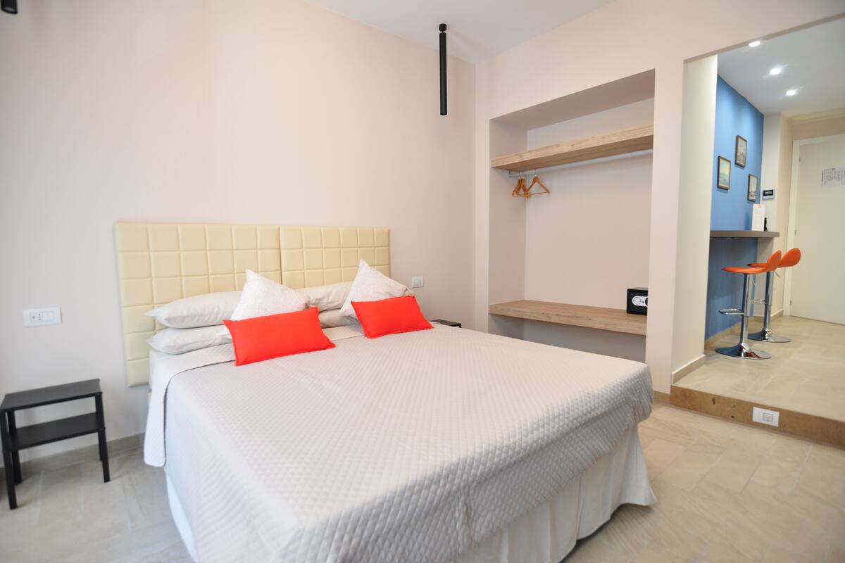 A bedroom with a large bed, a bedside table, and a wardrobe.