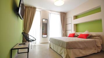 A hotel room with a bed, a chair, a TV, and a table.
