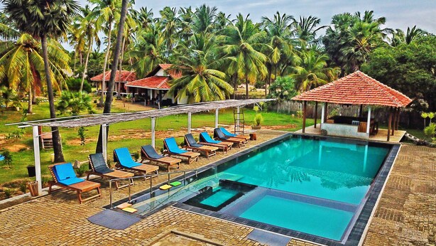 A pool area with lounge chairs and a gazebo. - Valampuri Kite Resort (Kalpitiya)