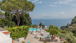 Zona junto a la piscina con sillones reclinables, una piscina pequeña y vista al mar.