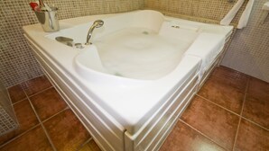 A bathroom with a large bathtub, a sink, and a toilet.