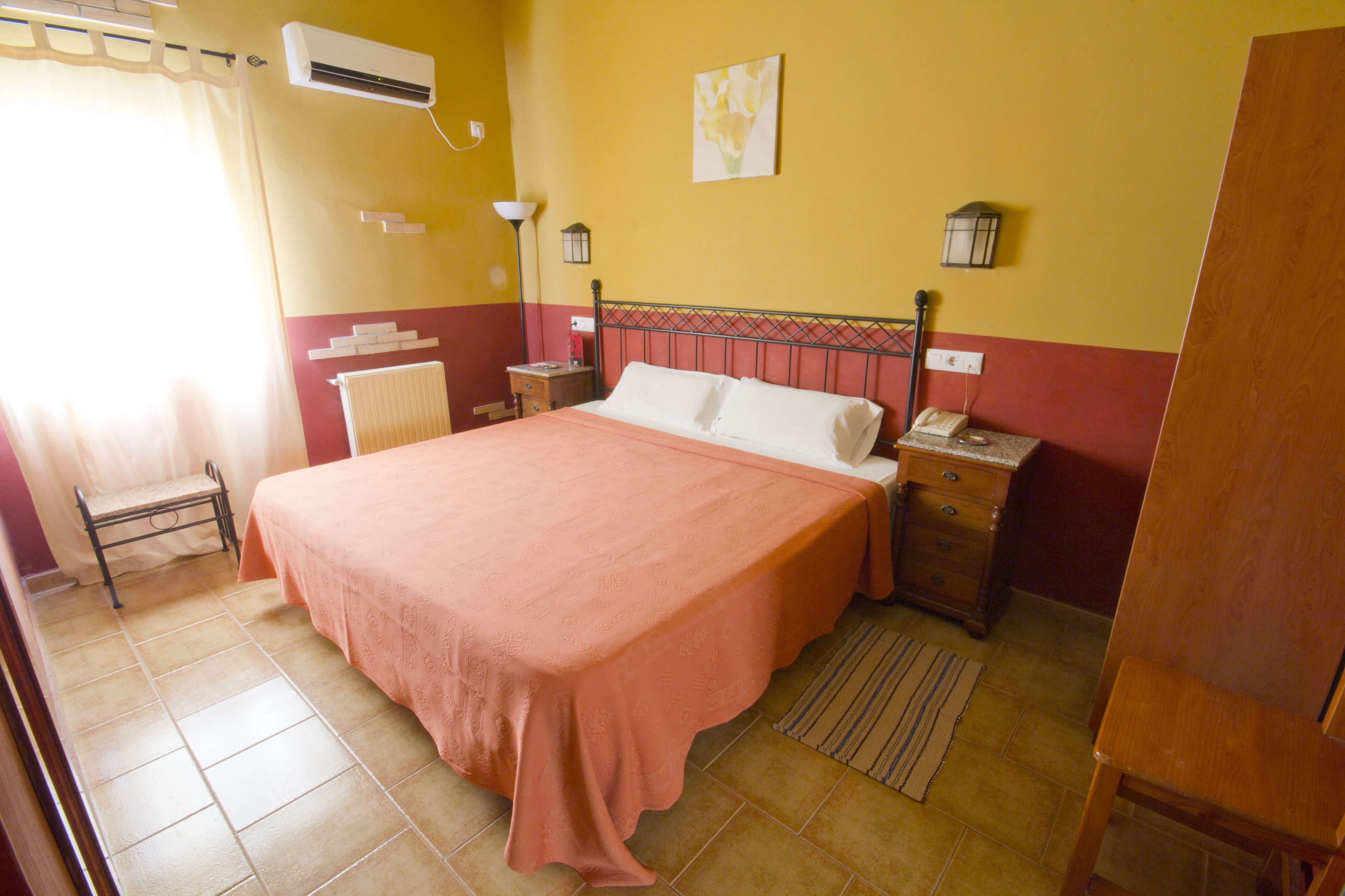 Une chambre à coucher avec un grand lit, une table de chevet, une lampe et un radiateur.