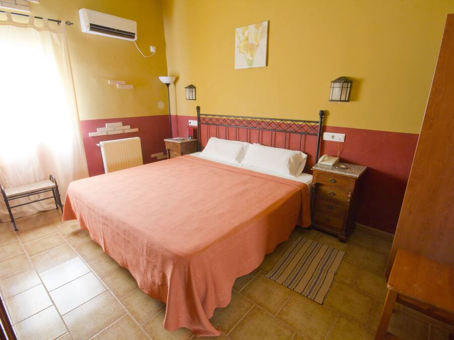 Une chambre à coucher avec un grand lit, une table de chevet, une lampe et un radiateur.