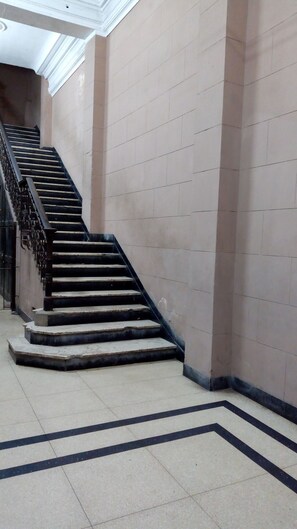 A staircase with black railings and beige tiled walls. - Jerome's Old Havana Apartment (Havana)