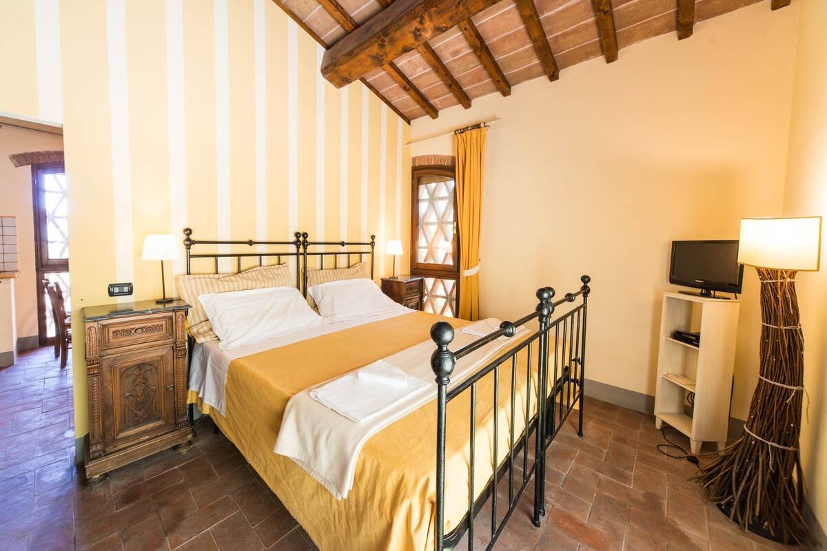 A bedroom with a bed, bedside tables, a TV, and a lamp.