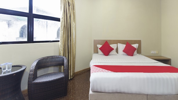 A hotel room with a bed, a chair, a small table, and a window with curtains. - Hotel Reno (Kuala Lumpur)