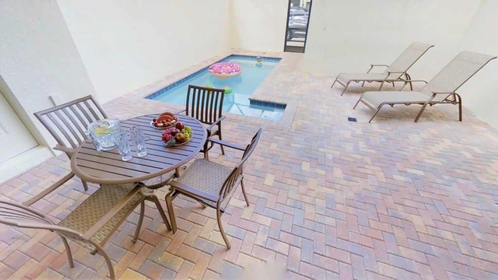 Un espace patio avec une piscine, une table entourée de chaises et des chaises longues.