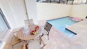 A pool area with a table and chairs, a pool, and a door. - Aco234120 - Windsor At Westside Resort - 4 Bed 3 Baths Townhome (Kissimmee)