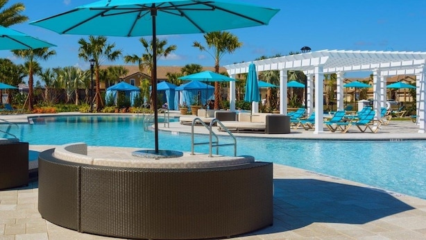A pool area with lounge chairs, umbrellas, and a pergola. - Aco234120 - Windsor At Westside Resort - 4 Bed 3 Baths Townhome (Kissimmee)