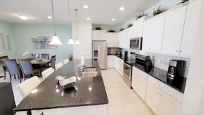 A modern kitchen with white cabinets, a granite countertop, and stainless steel appliances. - Aco234120 - Windsor At Westside Resort - 4 Bed 3 Baths Townhome (Kissimmee)