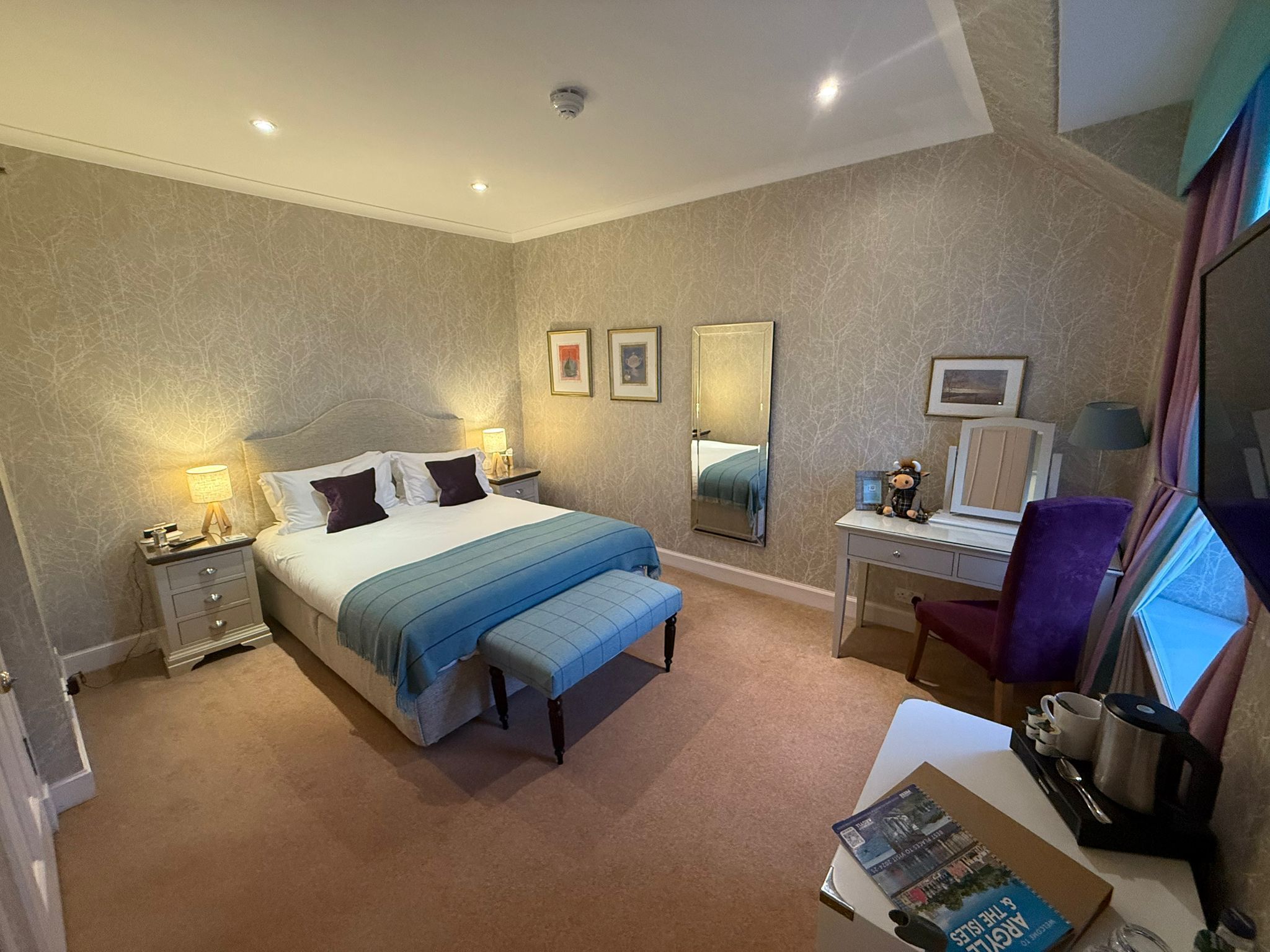 Une chambre d’hôtel comprenant un lit, des tables de chevet, un bureau, une chaise, un miroir et une fenêtre.