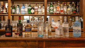 A bar with various bottles of alcohol and glasses on the counter. - The Airds Hotel & Restaurant (Appin)