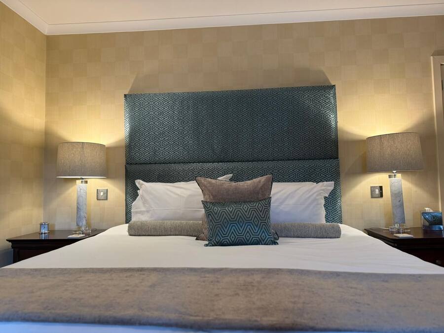 Una habitación de hotel con una cama grande, dos mesitas de noche y un cabecero estampado.