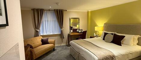 Une chambre d’hôtel avec un grand lit, un bureau, une chaise et un canapé.