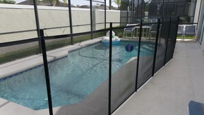 A swimming pool with a safety fence, a patio area with chairs, and a view of the surrounding neighborhood. - Ahr225 - Southern Dunes - 3 Bed 2 Baths Villa (Haines City)