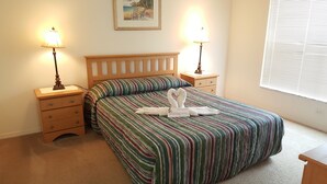A neatly made bed with striped bedding, two bedside tables with lamps, a wooden headboard, and a framed picture on the wall. - Ahr225 - Southern Dunes - 3 Bed 2 Baths Villa (Haines City)