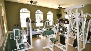 Ein Fitnessstudio mit Laufbändern, Krafttrainingsgeräten und einem Bereich für Übungen auf Matten.