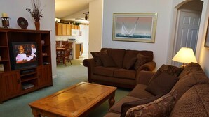 A living room with a brown sofa, a wooden coffee table, and a television on a wooden stand.